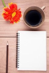 Gerbera flower,coffee, notebook and pencil on the wood table