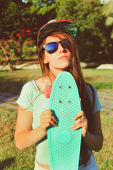 Beautiful teenage girl in sunglasses and a cap with a skateboard in her hands © Krent Arte