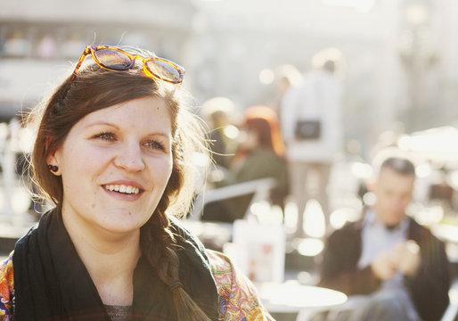 Happy woman looking away while sitting at sidewalk cafe on sunny day