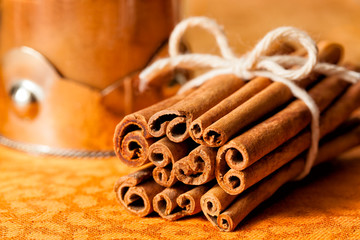 Cinnamon sticks tied in a bundle next to a glass jar ground spice. Close up