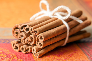 Cinnamon sticks tied bundle on a colorful cloth. Close up