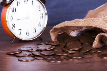 Bag of coins spilt over a wooden surface
