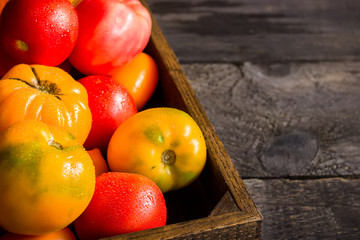 Red and yellow tomatos in wooden box.