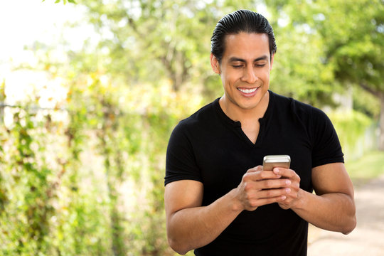 Hispanic Man Texting And Talking On His Phone.