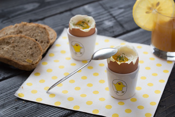 Soft boiled eggs with bread on white napkin with yellow dots.