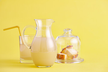 Glass jug of fresh pineapple juice on yellow
