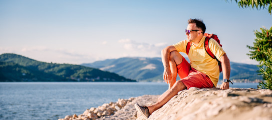 Man sitting on a stone dock by the sea