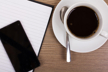 Notebook and coffee cup on a wooden surface