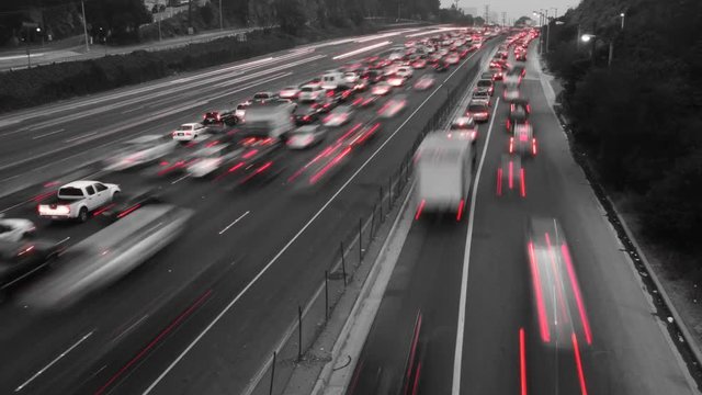 Time Lapse of traffic where the footage has been made black and white except for the red of the car's taillights.