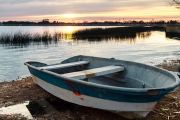 Single boat on the coast of a lake at sunset