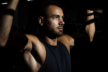 Handsome man training in clean modern gym on various machines