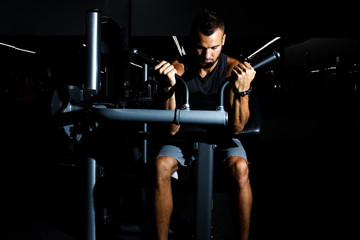Fototapeta na wymiar Closeup of a muscular young man lifting weights on dark backgrou
