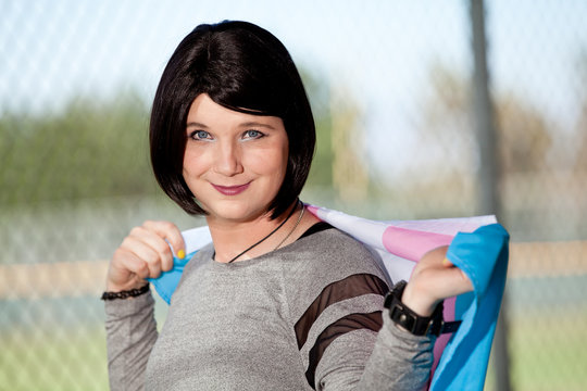 Transgender girl holding Trans Pride flag.