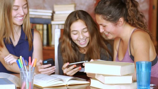 A group of pretty teenage girls laughing with their mobile devices