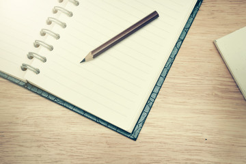 Pencil and open notebook on wood background in selective focus.