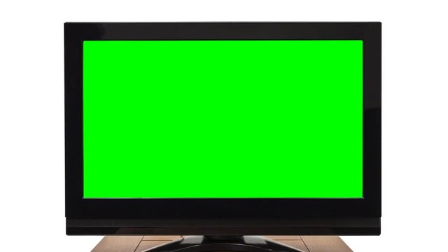 Flat screen television on white with zoom into chroma key green screen.