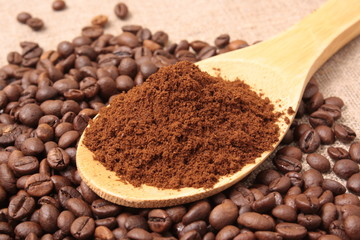 Ground coffee in a wooden spoon close-up on a background of coff