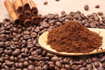 Ground coffee in a wooden spoon close-up on a background of coff