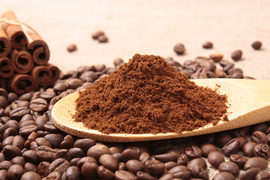 Ground coffee in a wooden spoon close-up on a background of coff