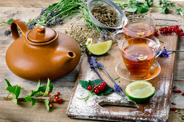 Fototapeta na wymiar Herbal tea with herbs, lime and berries on wooden board