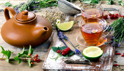 Fototapeta na wymiar Herbal tea with herbs, lime and berries on a wooden board