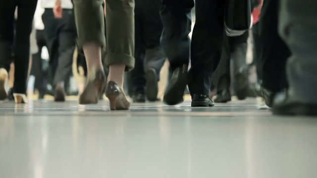 Hundreds of office workers walking past as they exit a busy train station as they rush to their jobs.