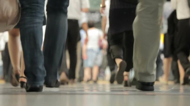 Hundreds of office workers walking past as they exit a busy train station as they rush to their jobs.