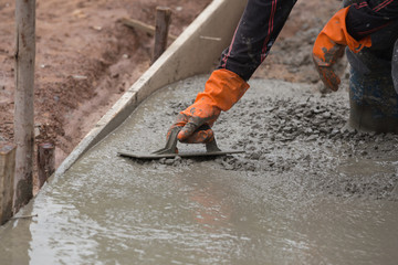 hand of worker use trowel plastering a newly poured concrete flo