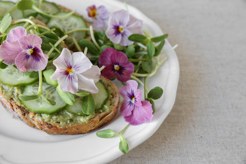 Fototapeta na wymiar avocado , cucumber, sunflower sprout and edible flowers on sourdough toast