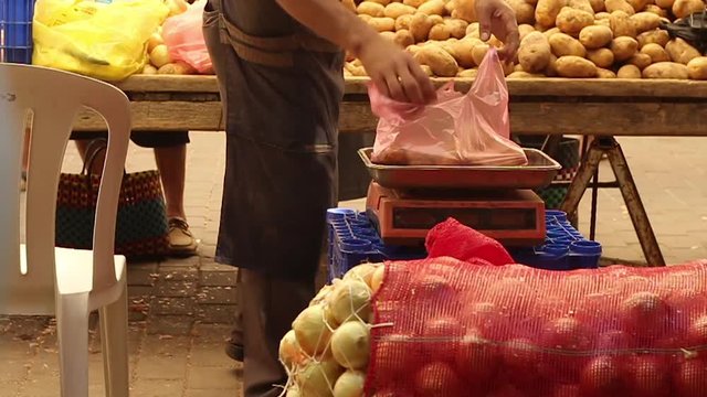 A market trader weighing a bag of potatoes for a customer at a Turkish street market filmed at 60fps and slowed in post