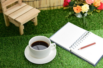 Writing on copy space note book on green grass Background.With s