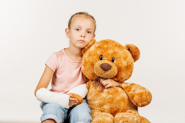 Young girl with broken arm is looking at the camera and hugging