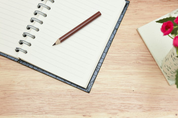 Pencil and open notebook on wood background in selective focus.