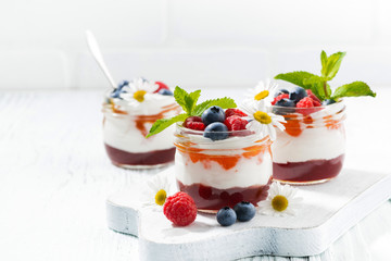 dessert with jam, cream and fresh fruit in a glass jars 