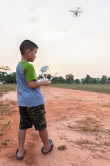 Portrait of kid with quadcopter drone outdoors. Happy boy playing with flying drone with camera controlled by smartphone