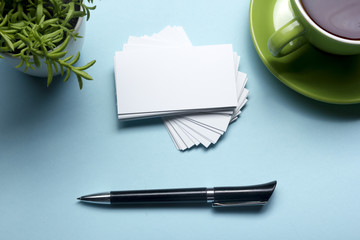 Business card blank over coffee cup and pen at office table. Corporate stationery branding mock-up