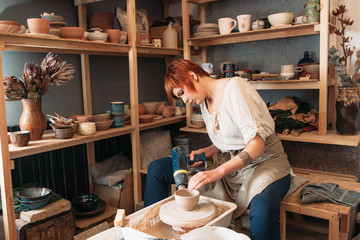 Pottery drying with special dryer. Carefully working young female potter. Small business of woman