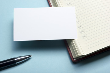 Business card blank over notepad at office table. Corporate stationery branding mock-up