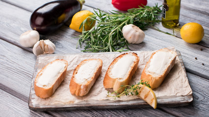 Slices of bread with butter. Piece of lemon and herb. Crispy toasts for bruschetta. Preparation of morning snack.