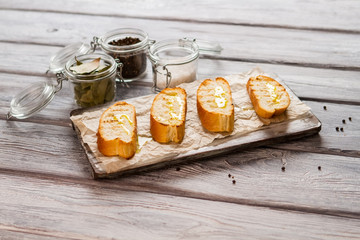 Slices of bread with oil. Jar with salt. Prepare delicious snack at home. Crispy grilled baguette.