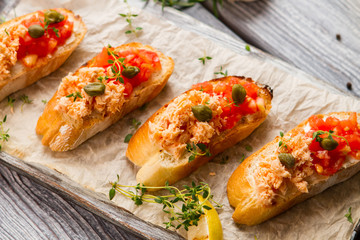 Toasts with tomatoes and capers. Fish meat and grilled lemon. Food of natural ingredients. Delicious salmon bruschetta.