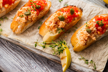 Grilled lemon and toasts. Fish meat on baguette slices. Delicious food cooked at home. Proven recipe of salmon bruschetta.