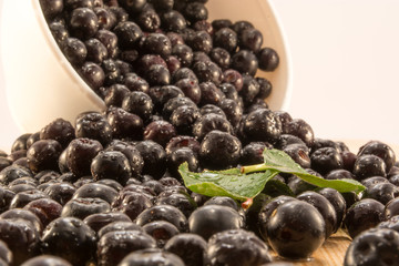 Bowl full of aronia spilled on wooden table