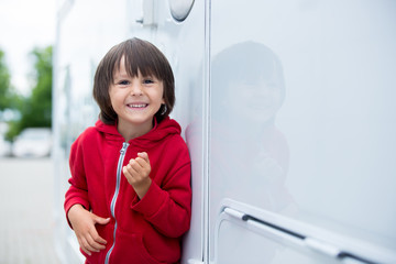 Cute kid, sitting on a doorway of a caravan