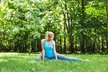Naklejka na ściany i meble Woman doing yoga exercises in the park.