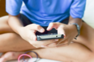 Blurry of teenage male hands play with phone at home.