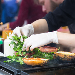 Chef making beef burgers outdoor on open kitchen international food festival event. Street food...