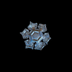 Snowflake isolated on black background. This is macro photo of real snow crystal with glossy surface, six broad arms and large central hexagon with relief details.