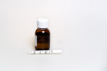 Tablets, cough syrup with a measured syringe, dressing on the face, a thermometer on a white background. Proceeds from the common cold and flu.
