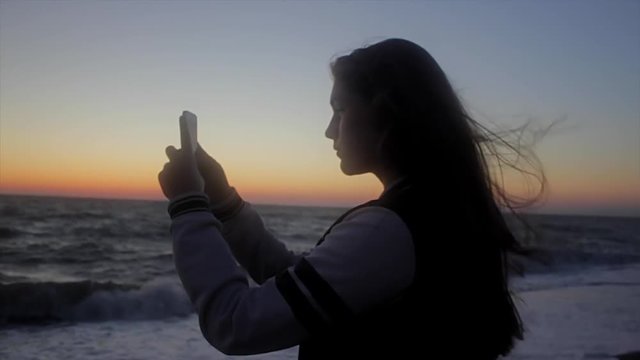 Girl taking photo on the beach. Handheld shot